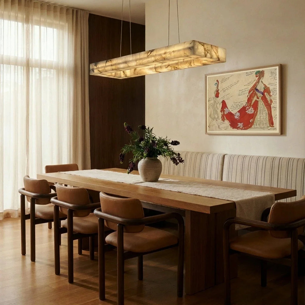 Clérachic rectangular alabaster chandelier above a long oak dining table with leather chairs and a linen curtain.