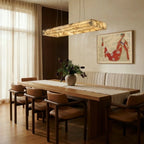 Clérachic rectangular alabaster chandelier above a long oak dining table with leather chairs and a linen curtain.