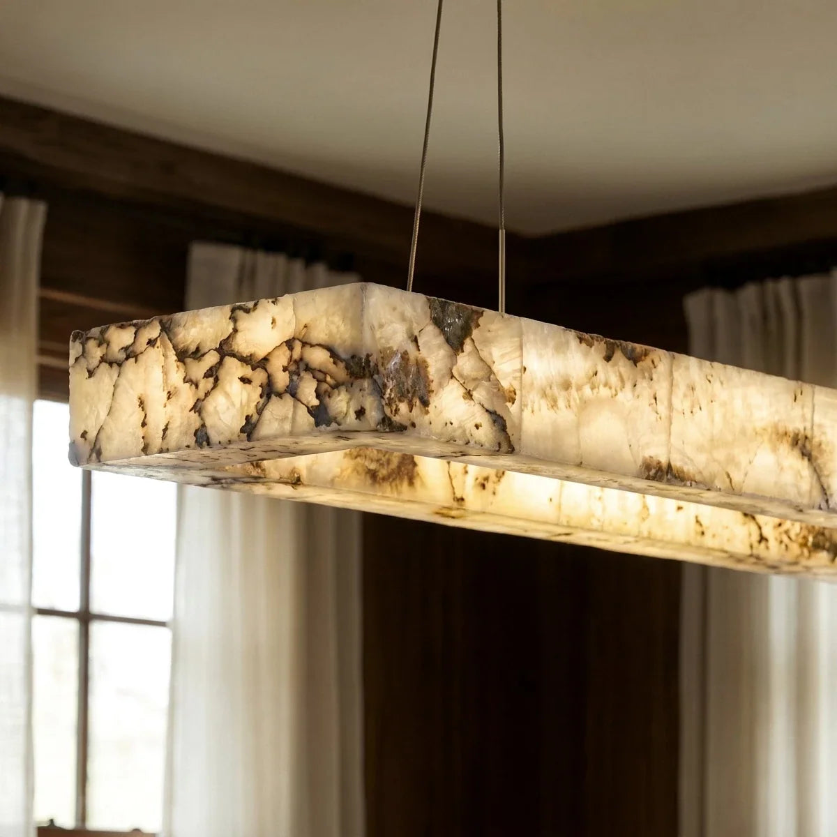 Clérachic alabaster chandelier up close, dark veins and amber patches glowing through the stone shade.