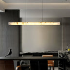 The Clérachic bar lit warm above a dark kitchen island, its glow washing the concrete wall behind the seating.