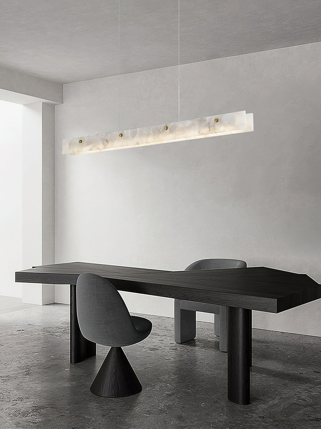 The Clérachic pendant in a minimalist room, hung above a sculptural black table on a polished concrete floor.