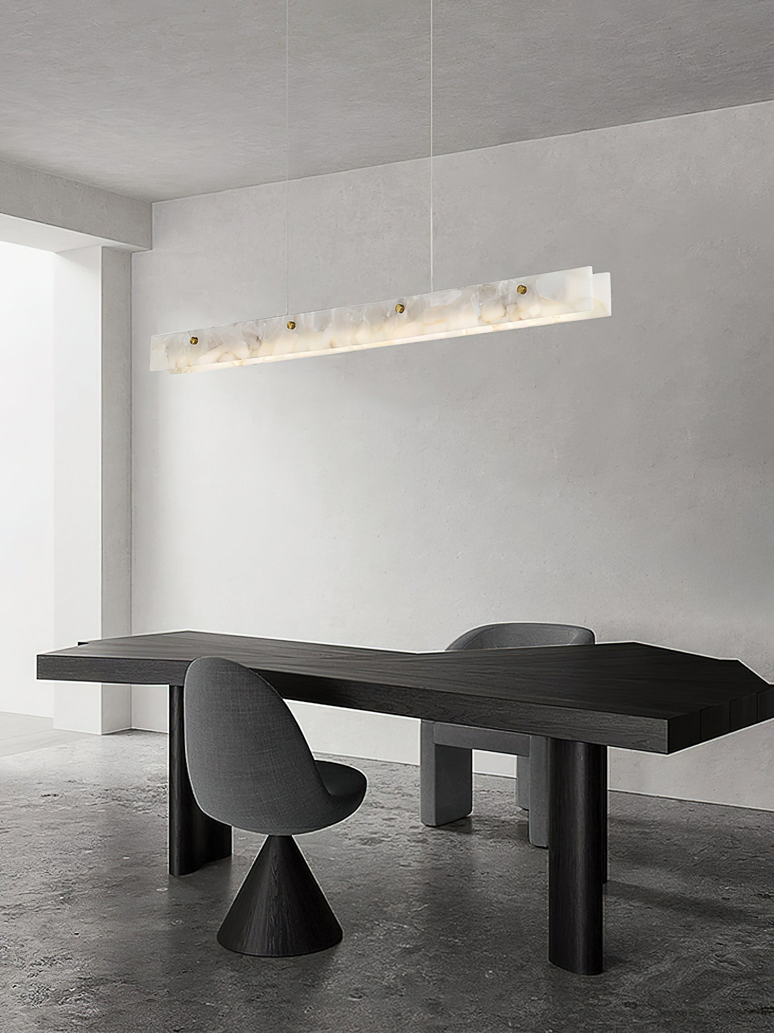 The Clérachic pendant in a minimalist room, hung above a sculptural black table on a polished concrete floor.