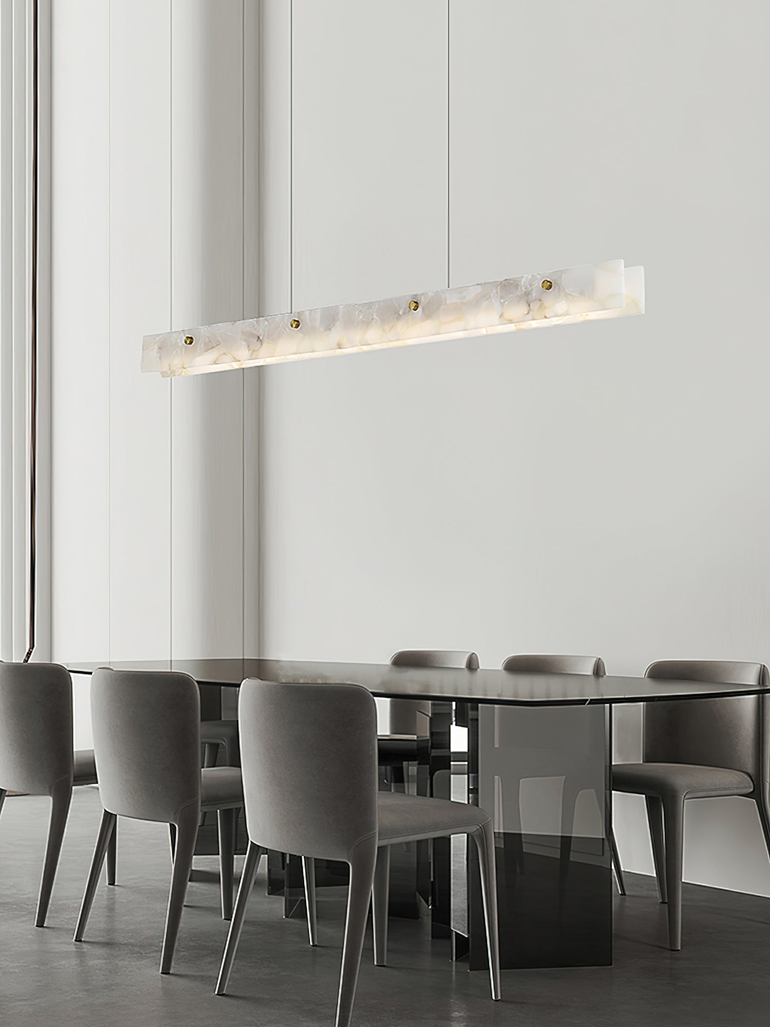 Clérachic linear pendant lit above an oval table ringed with grey upholstered chairs in a quiet dining corner.