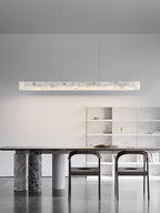 The Clérachic bar glowing above a marble-base dining table, with open shelving along the wall behind.