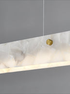 The Clérachic diffuser in close-up, a brushed brass stud set into the cloudy alabaster with light spilling from the lower edge.