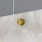 Clérachic brass stud shown in macro against the alabaster face, with the fine steel suspension cable rising above it.
