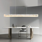 Clérachic pendant suspended in a curved grey room above a pale stone table with a single low chair.