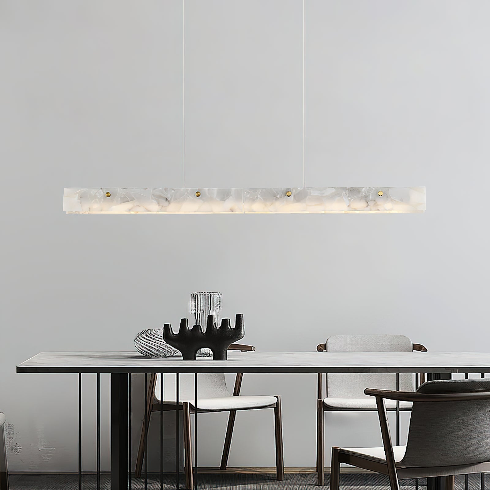 Clérachic alabaster pendant lit above a white dining table with dark timber chairs in a calm, pale room.