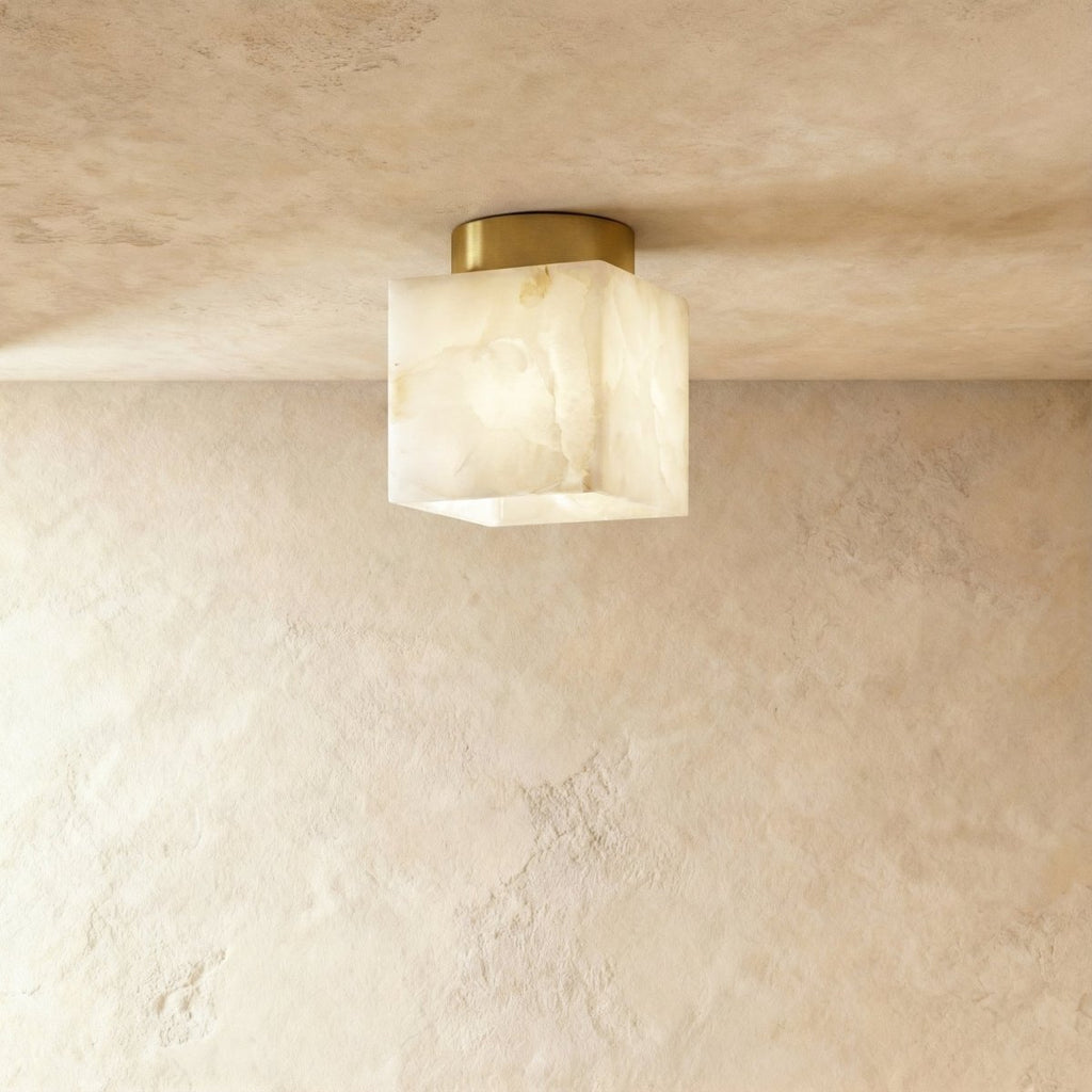 Clérachic square veined alabaster ceiling light on a round brushed brass canopy, glowing softly against a limewash ceiling.
