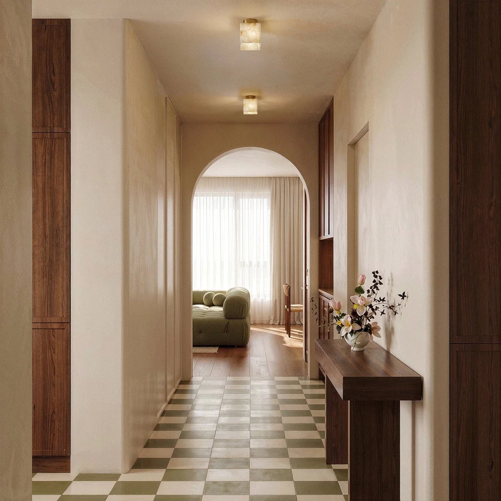 Clérachic two square alabaster ceiling lights lit along a hallway with an arched opening and a green checkered floor.
