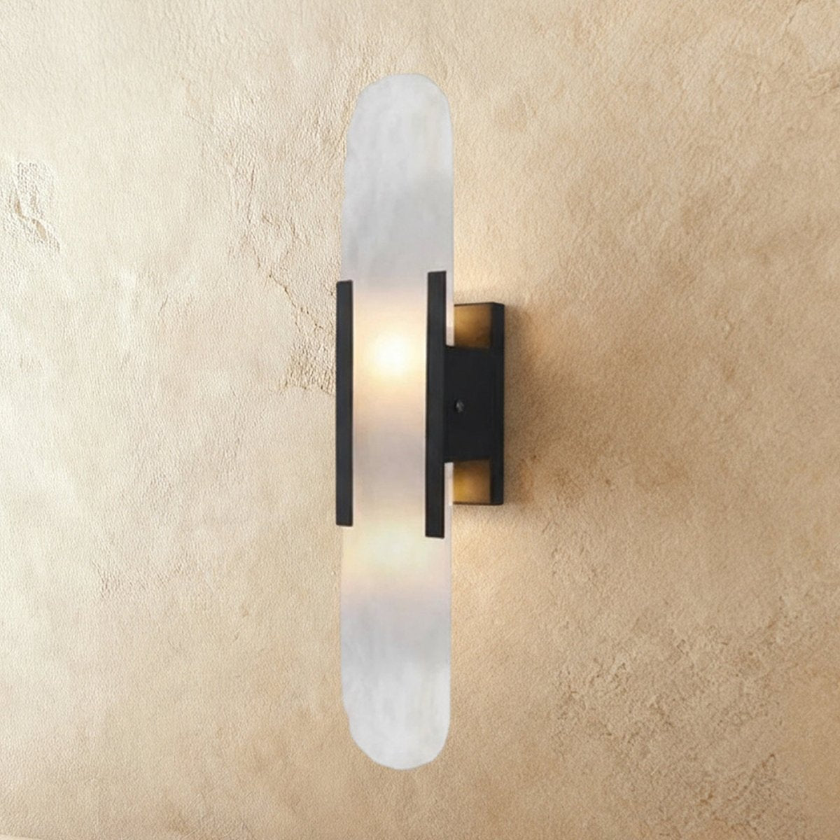 Clérachic tall wall light with a veined alabaster shade, black bars and a black wall plate, softly lit.