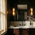 Pair of Clérachic black wall lights with veined alabaster shades flanking a mirror above a marble vanity.