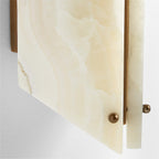 Close-up of the Clérachic wall sconce, a brass ball finial pinning the honey-veined stone panel to its brass frame.