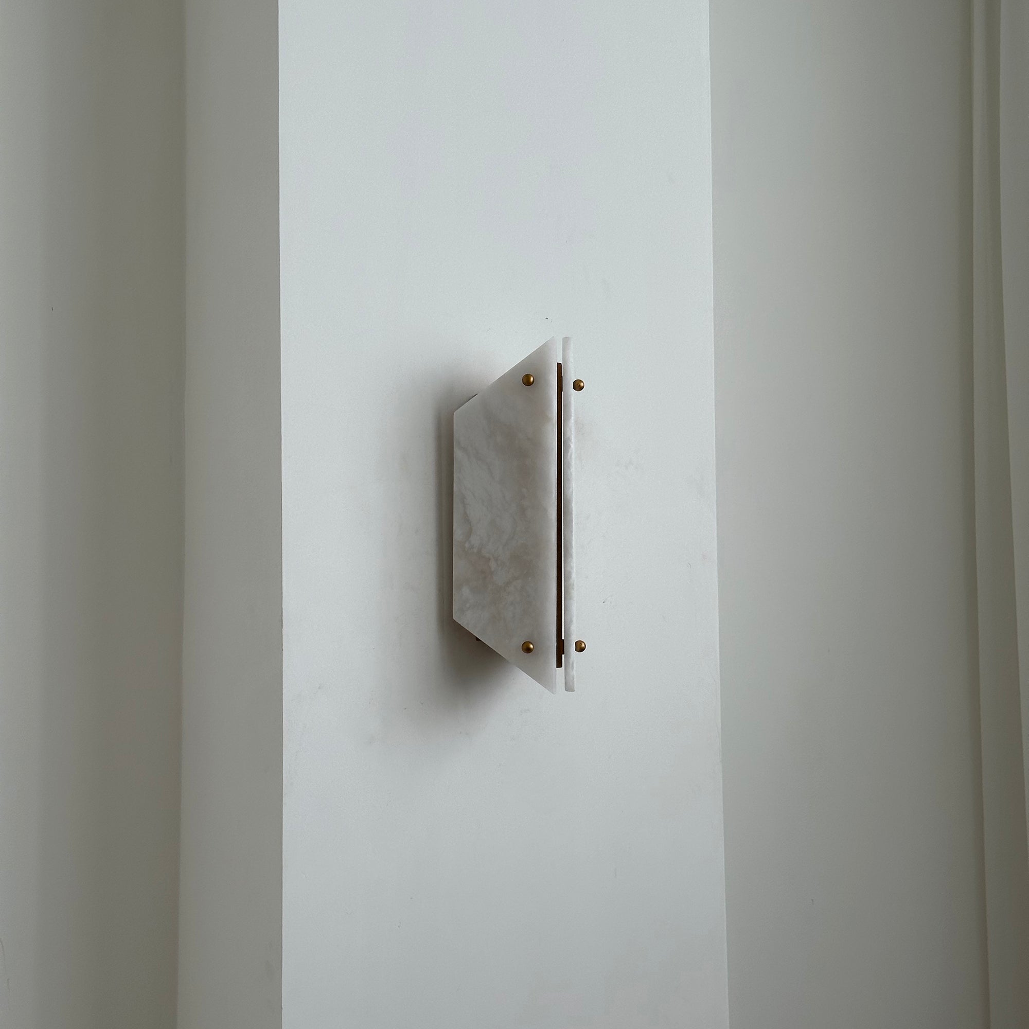 Unlit Clérachic alabaster sconce seen from the side, sitting only a few centimetres proud of a white wall.