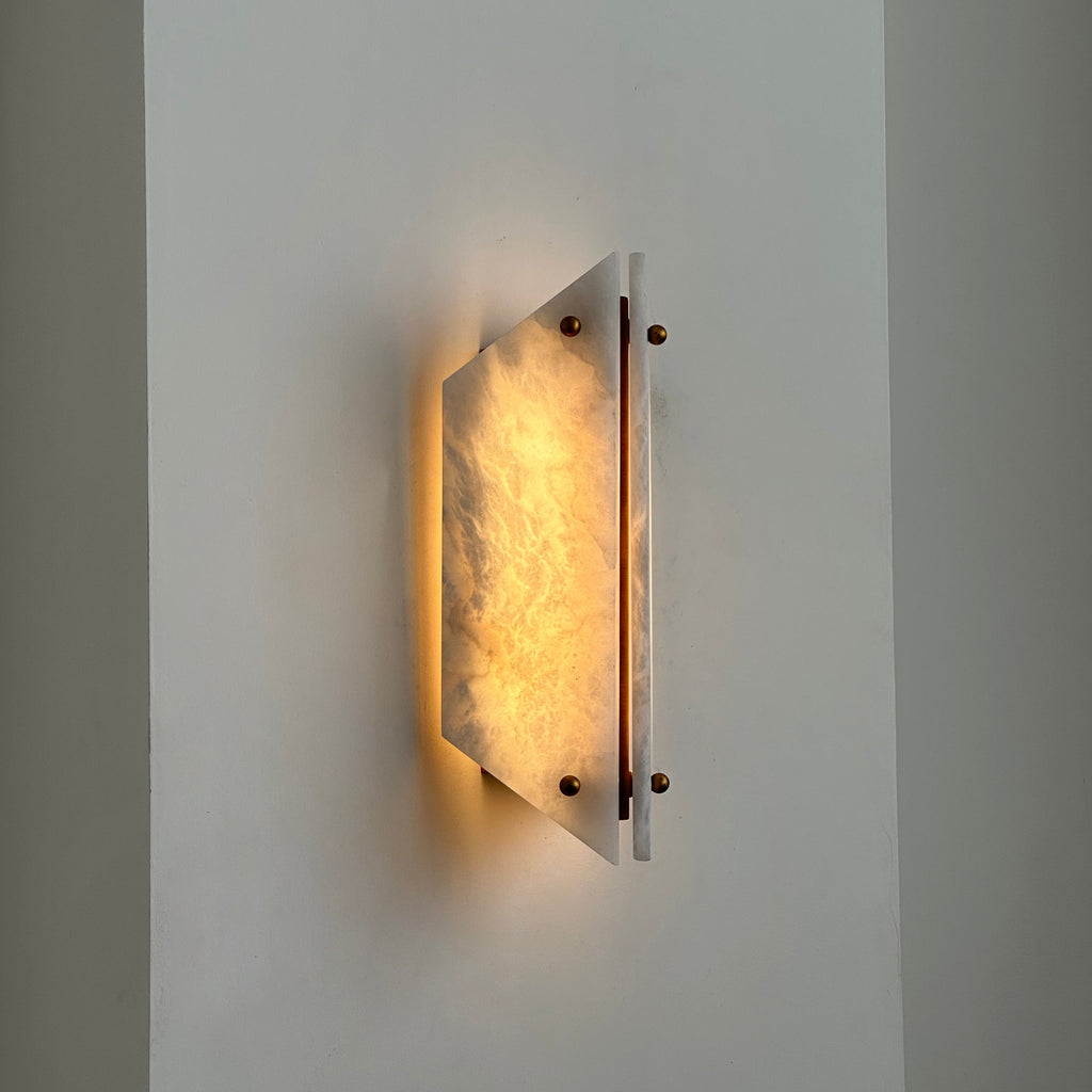 Lit Clérachic stone sconce on a corner wall, warm light spilling above and below the glowing alabaster panel.