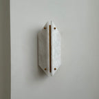 Clérachic alabaster wall sconce off, its two panels forming a pale faceted shield beside a wall corner.