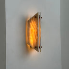Clérachic jade wall sconce lit at an angle, warm amber banding showing through the stone beside its brass bar.