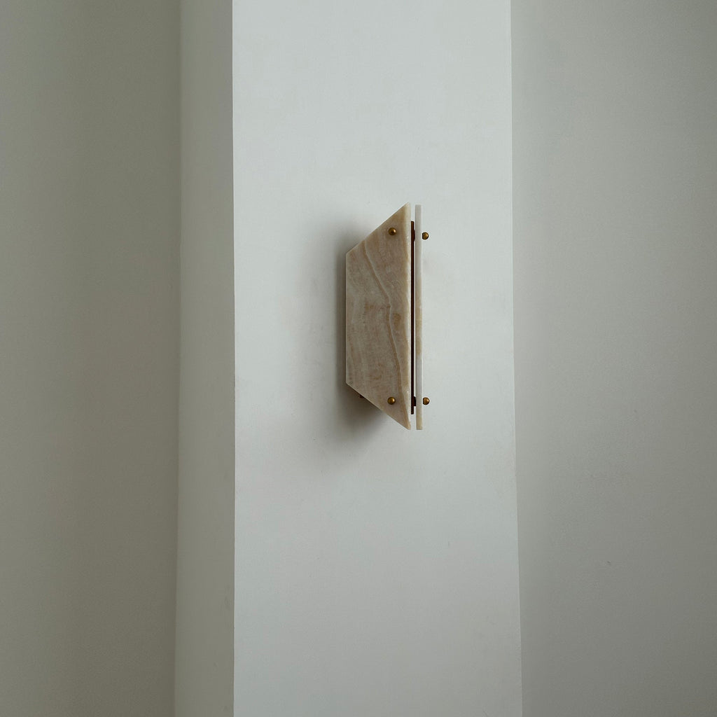 Unlit Clérachic jade sconce on a bright wall corner, warm honey stone paired with a slim white side panel.