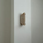 Unlit Clérachic jade sconce on a bright wall corner, warm honey stone paired with a slim white side panel.