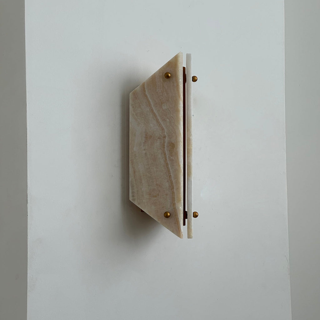 Side view of the unlit Clérachic jade sconce, the angled stone panel projecting a hand's width from the wall.