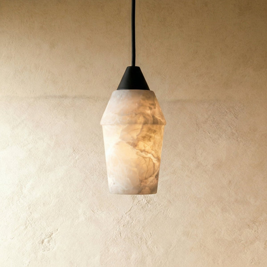 Clérachic alabaster pendant with a dark conical cap on a black cord, glowing warm against a pale limewash wall.