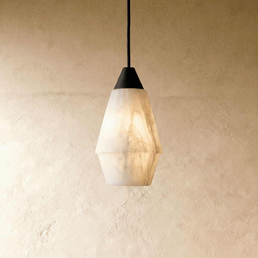 Clérachic tapered alabaster pendant with a black cap and cord, white veined stone glowing against a plaster wall.