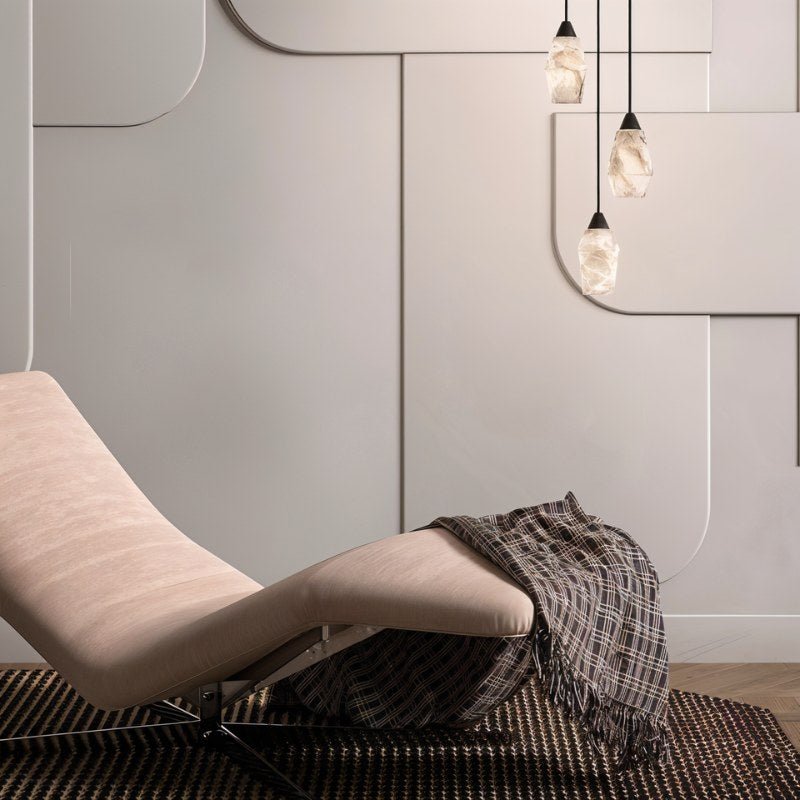 Clérachic trio of lit alabaster pendants hanging beside a pale curved lounge chair, throw and panelled wall.