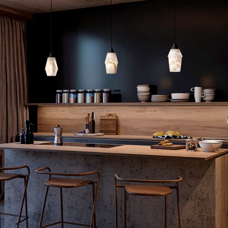 Clérachic three alabaster pendants glowing over a timber kitchen island with tan stools and a dark wall behind.