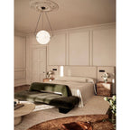 The Clérachic pendant seen from across the panelled bedroom, small and warm above the bed and green bench.