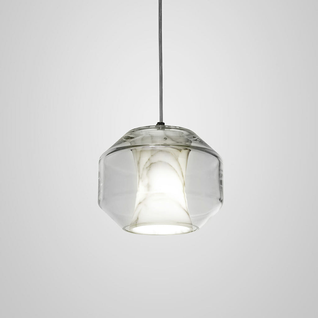The wide gem-cut barrel of the Clérachic Alabaster Pendant Light, lit so the stone reads warm inside the angular clear glass shell.