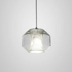 The wide gem-cut barrel of the Clérachic Alabaster Pendant Light, lit so the stone reads warm inside the angular clear glass shell.