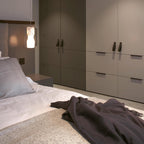 A single Clérachic Alabaster Pendant Light dropped beside a bed as a bedside light, glowing warm above a low nightstand.