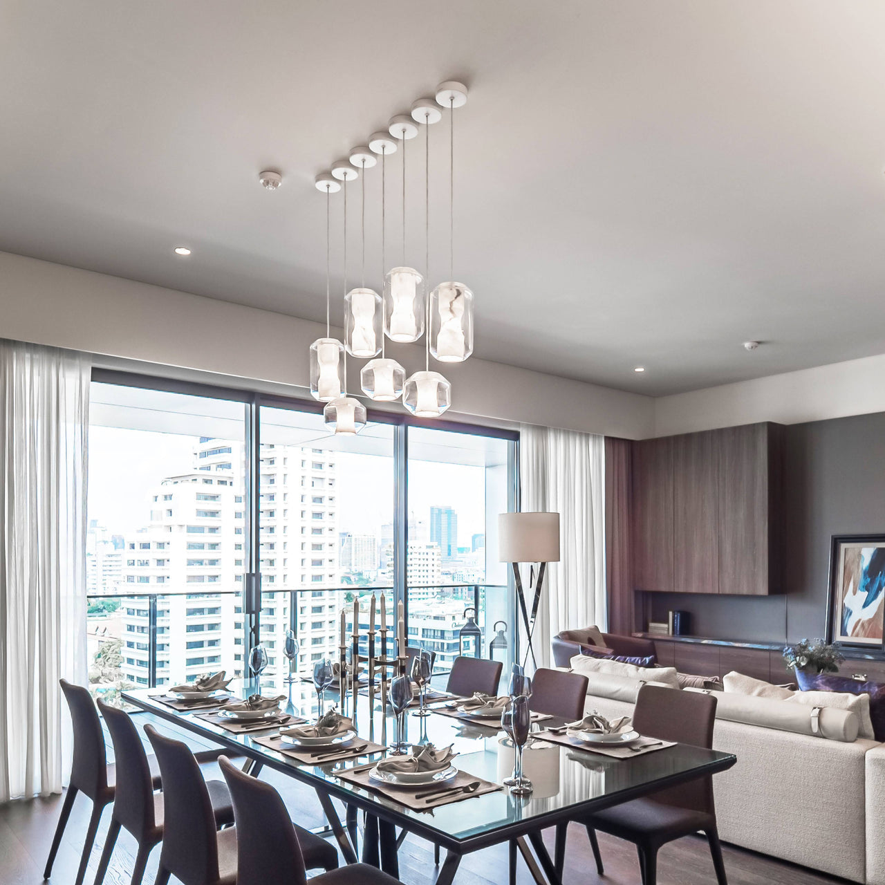 Nine Clérachic Alabaster Pendant Lights clustered at staggered drops above a long dining table in a city apartment.