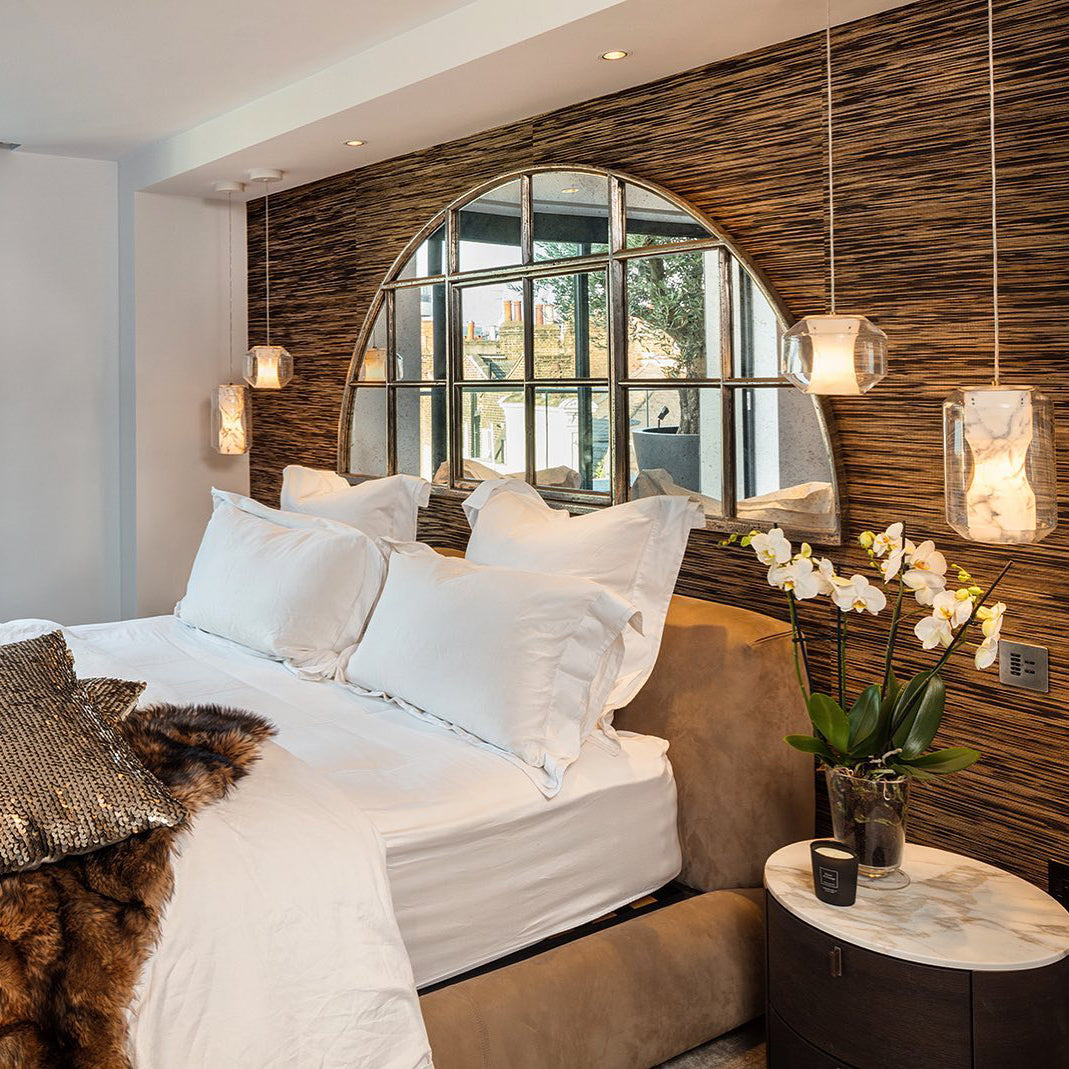 Clérachic Alabaster Pendant Lights hung in pairs either side of a bed, lighting a bedroom with a reeded timber wall.