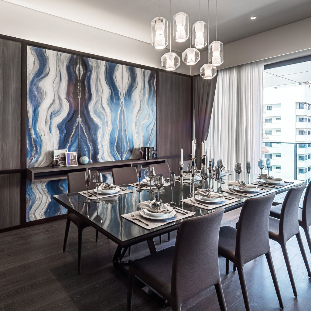 A nine-piece run of Clérachic Alabaster Pendant Lights lit over a set dining table, against a blue agate stone wall panel.