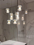 Six Clérachic Alabaster Pendant Lights lit in a tight cluster, doubled in the mirrored panel of a marble-lined room.