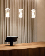 Three Clérachic Alabaster Pendant Lights in a level row above a curved oak counter, backed by a full-height linen curtain.