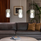 Three Clérachic Alabaster Pendant Lights hung low over a round table in a living room with a brown leather sofa.