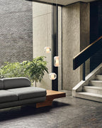 Clérachic Alabaster Pendant Lights hung at three heights down a stairwell wall, lit against daylight in a brick entrance hall.