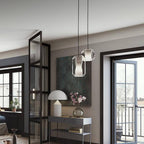 Two Clérachic Alabaster Pendant Lights on black cables in a hallway, hung above a console of magnolias by the balcony doors.
