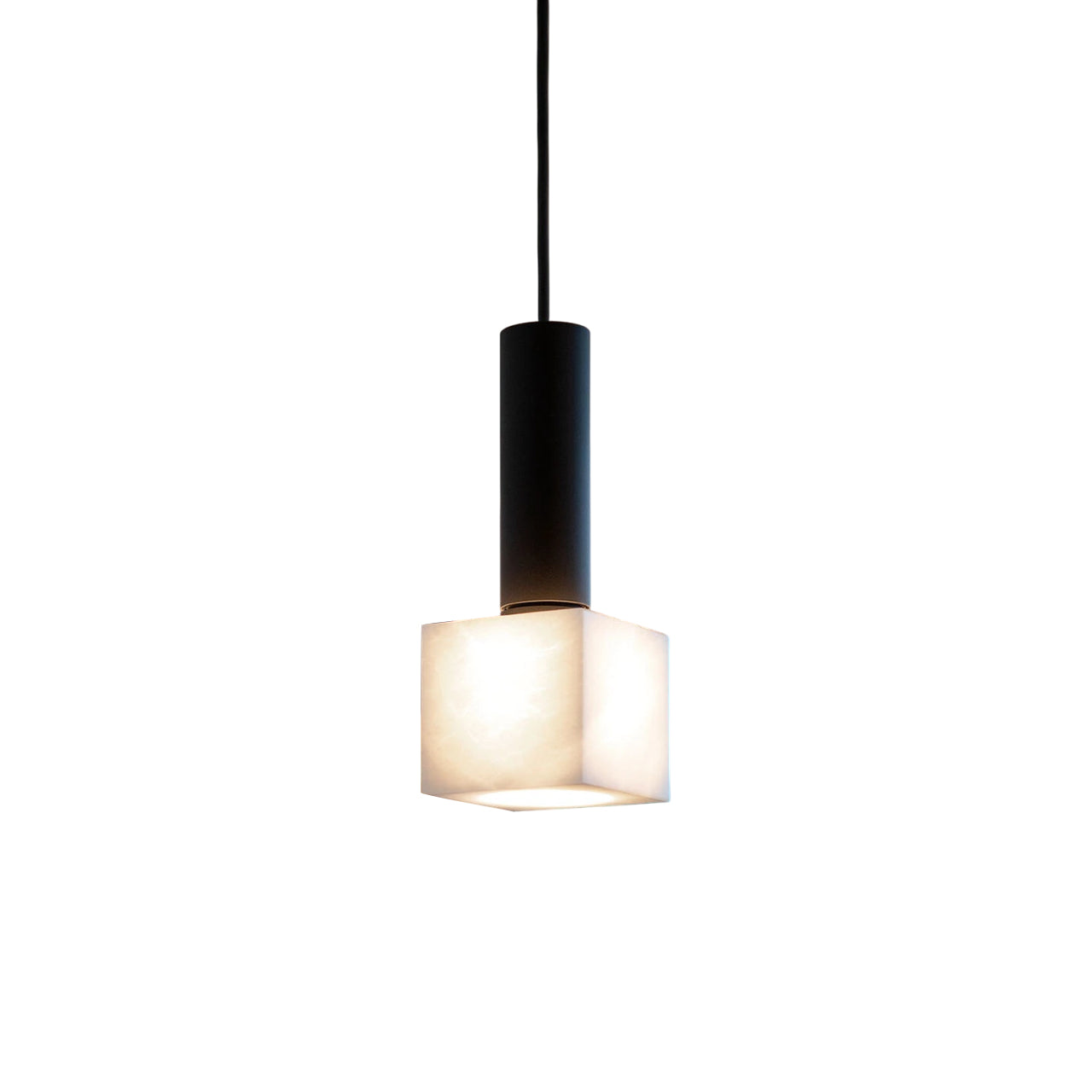 Clérachic Alabaster Pendant Light on its matte black stem, the small cube shade glowing warm against a white studio backdrop.