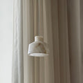 The Clérachic Alabaster Pendant Light seen side on, its white stone shade unlit and faintly veined against sheer drapes.