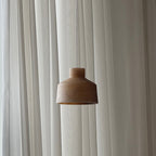The brown shade of the Clérachic Alabaster Pendant Light, its stepped drum profile lit by daylight through sheer curtains.