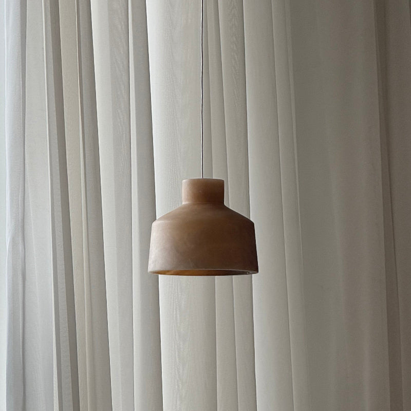 The brown shade of the Clérachic Alabaster Pendant Light, its stepped drum profile lit by daylight through sheer curtains.