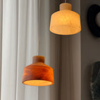 Clérachic Alabaster Pendant Light in both stone colours lit together, the brown shade burning amber beside the pale cream one.
