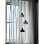 Clérachic Alabaster Pendant Light cluster seen unlit in cool daylight, two pale shades above a darker brown one by the window.