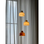 Clérachic Alabaster Pendant Light cluster lit against grey drapes, the lowest shade glowing deep amber below two paler ones.