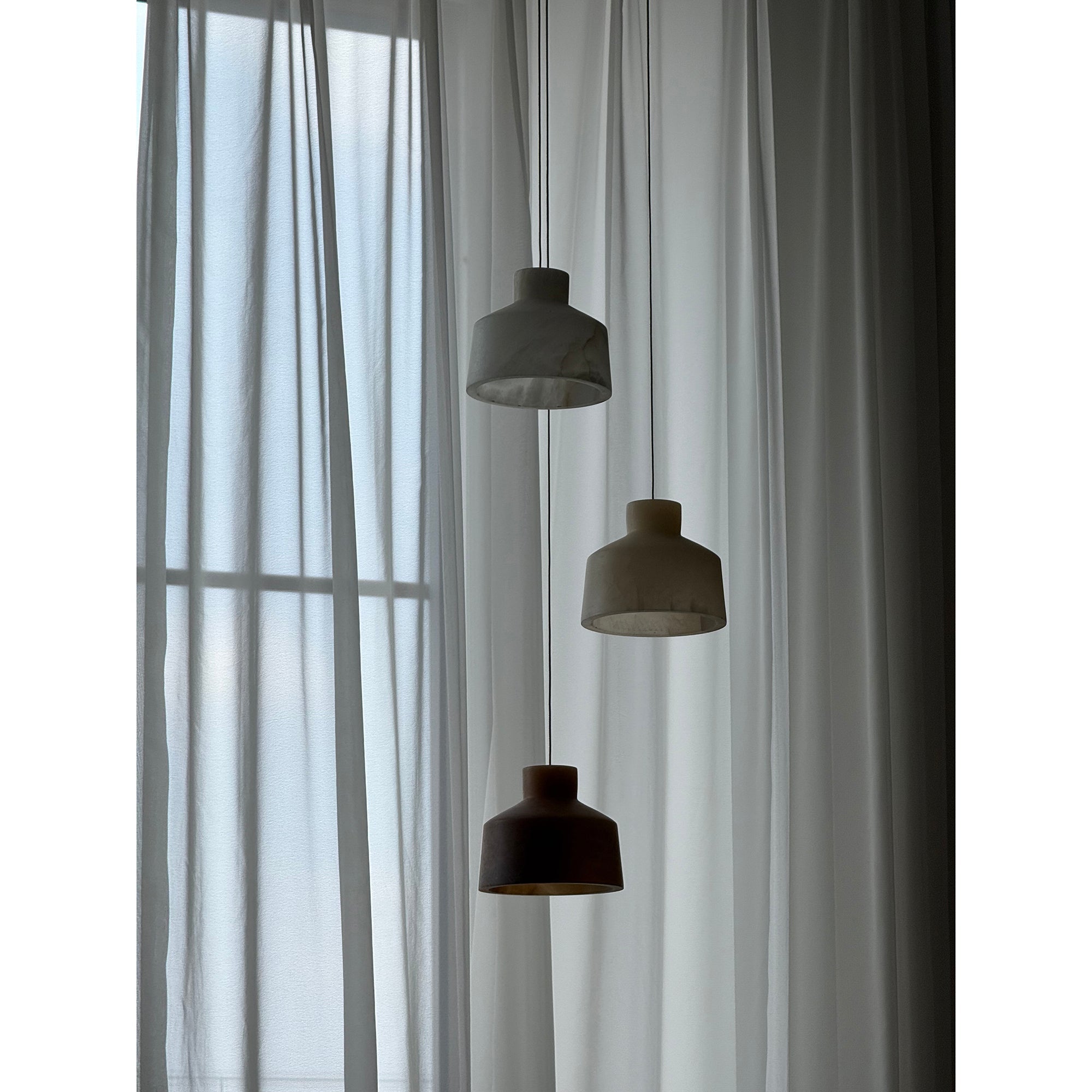Clérachic Alabaster Pendant Light cluster unlit at the end of the day, three stone shades silhouetted against sheer curtains.