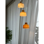 Clérachic Alabaster Pendant Light cluster viewed from below, sunlight on the curtains and the lowest shade glowing warm amber.