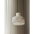 Close view of the Clérachic Alabaster Pendant Light, the stepped drum shade cut from white stone with faint amber seams.